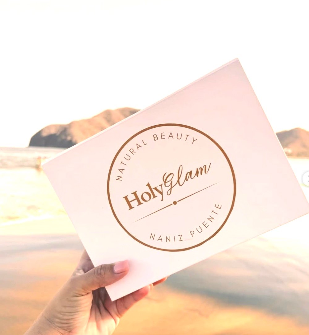 Caja de regalo HolyGlam Natural Beauty sostenida frente al mar.
